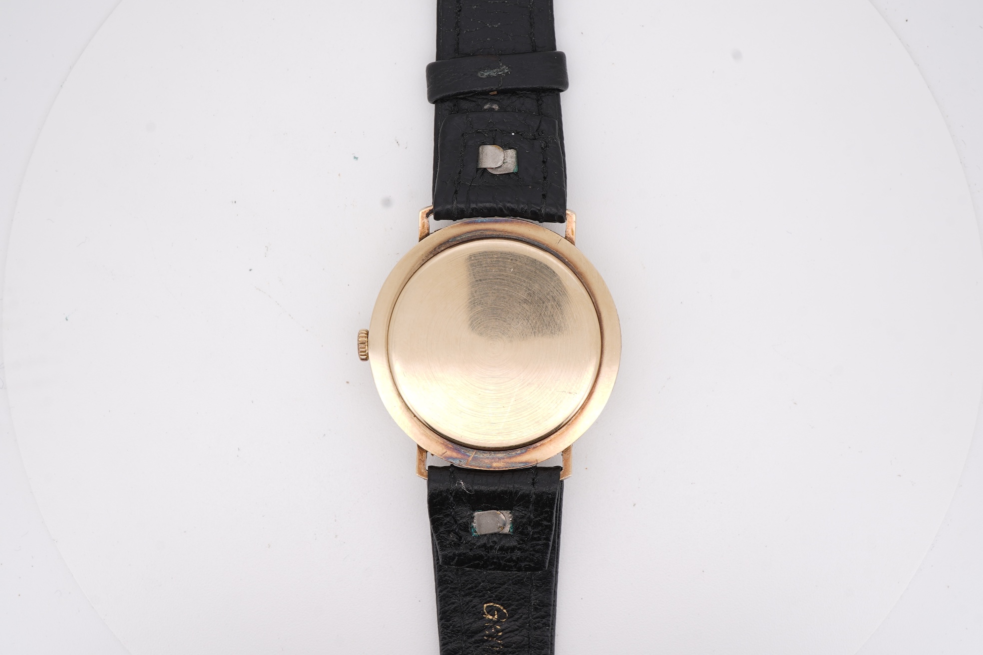 A gentleman's yellow metal Garrard manual wind wrist watch, with baton numerals and date aperture, case diameter 34mm, on a black leather strap.